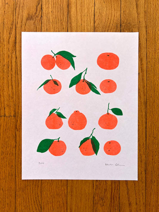 a loose grid of 12 satsumas are printed four rows of three on a white cardstock. Small simple pencil facial expressions are drawn on each, creating a range of expressions and dynamics between them. Some look away  perhaps lonely, some gazing at one another lovingly, others content and neutral. 