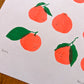A close up photo of the lower left corner of the print, showing the hand penciled year "2024". Five of the printed satsumas and be seen, as well as the Risograph texture and color overlay of the green leaves printing atop the fluorescent orange peels. 