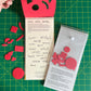 Hanson’s hand peels up the vertically coil bound foam cover to fully reveal the books title page. A second copy is flipped over to display the back cover, featuring a clear plastic envelope which contains a set of dicut foam cut out shapes (the inverse of the cover) behind it stamped making instructions are printed onto a gray card stock.